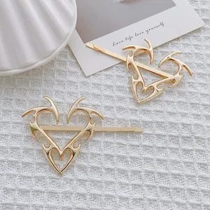 Detalle de dos pinzas para el cabello doradas Y2K con picos tribales en tela blanca