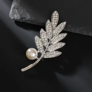 Élégante broche en forme de feuille avec strass brillants et une perle blanche ronde