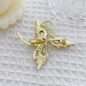 Élégante broche papillon dorée avec des ailes en cristal sur un tissu blanc doux