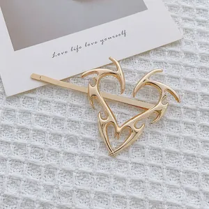 Primer plano de pasador dorado con diseño de corazón de llamas y espinas huecas
