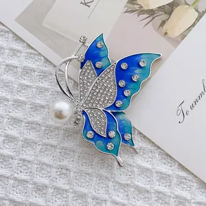 Elegant butterfly brooch with blue enamel wings, sparkling crystals, and white pearl detail