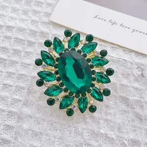Macro view of French luxury brooch with green crystals and oval emerald glass stone