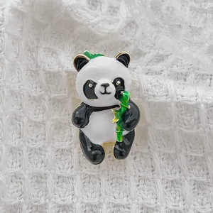 Cute cartoon panda brooch holding bamboo made of enamel alloy on white knit background