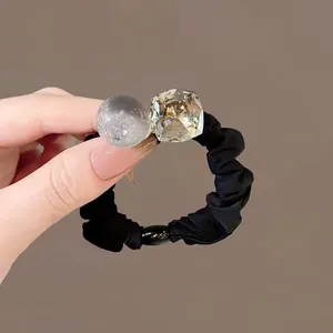 Dettaglio elastico per capelli nero con sfera glitterata grigia e cristallo trasparente