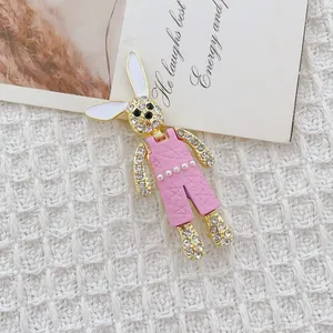 Encantador broche de conejo con strass y peto rosa sobre un fondo de tela de tweed