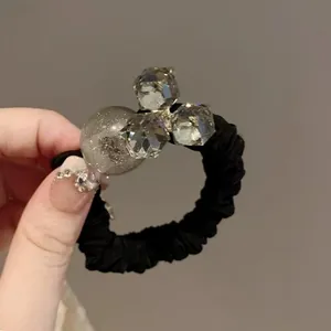 Dettaglio dell'elastico a pieghe nero con cristalli sfaccettati e ciondolo glitterato