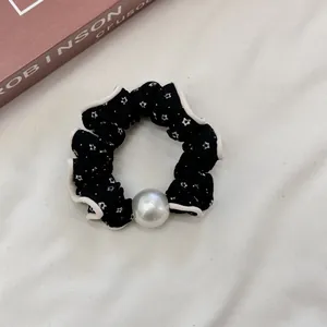 Detalle de coletero negro con estrellas, borde de encaje y adorno de perla grande