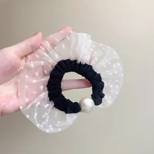 Detalle de coletero con volantes de malla con lunares blancos y perla de imitación