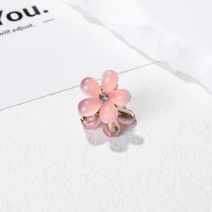 Détail d'une mini pince à cheveux camélia avec pétales roses et base en métal doré