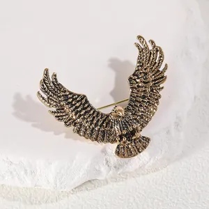 Vintage golden eagle brooch with detailed feathers on a minimalist stone background