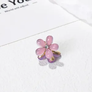 Macro d'une pince à cheveux camélia en résine rose avec strass blanc et base dorée