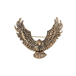 Minimalist vintage gold eagle brooch with detailed feather embossing on white background