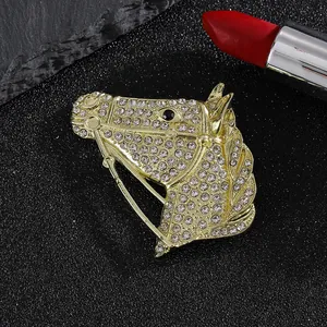 Golden horse head brooch with white rhinestones on a textured black and grey background