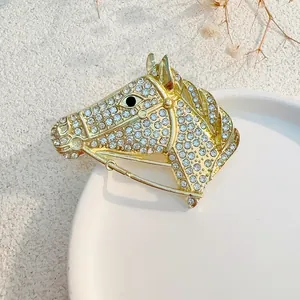 Golden horse head brooch with sparkling rhinestones on a white ceramic plate