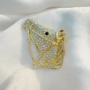 Detailed close-up of a gold horse head brooch encrusted with sparkling rhinestones on silk