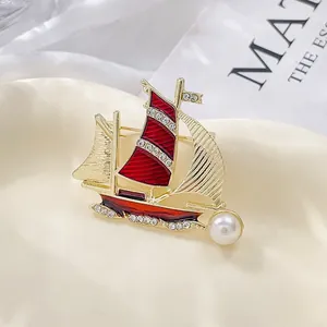 Elegante broche de velero en oro con esmalte rojo, pedrería blanca y una perla