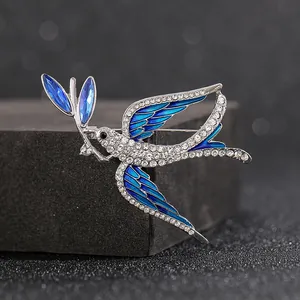 Elegant silver swallow brooch with blue crystals and rhinestones on black stand