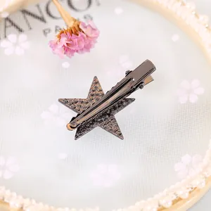 Chic gunmetal star hair clip with rhinestone accents on a decorative display plate