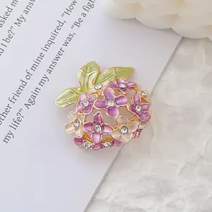 Detail showing purple enamel daisy flowers and green leaves with rhinestones on golden brooch