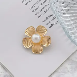 Gros plan détaillé d'une broche fleur dorée avec perle centrale sur un livre