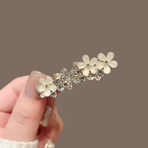Détail d'une barrette fleur dorée avec pierres œil de chat et strass brillants