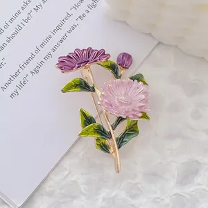 Detail of floral enamel daisy brooch with purple and pink flowers on book pages