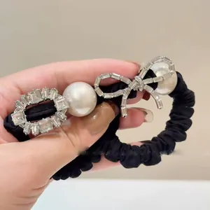Close-up of black satin scrunchie with large pearls and sparkling rhinestone bow detail