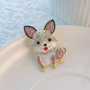 Dettaglio della spilla a cane con strass rosa e bianchi su base in metallo dorato