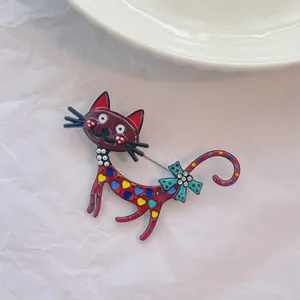 Broche chat en émail artistique avec motifs colorés et perle sur papier blanc