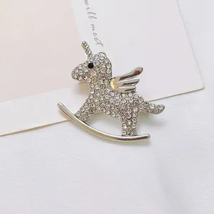 Close-up of a silver unicorn brooch with sparkling white rhinestones on white fabric