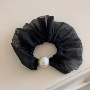 Elegant black ruffle scrunchie with a large lustrous white pearl accent for hair styling