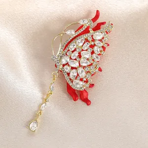 Luxueuse broche papillon rouge avec strass brillants et pampille dorée élégante