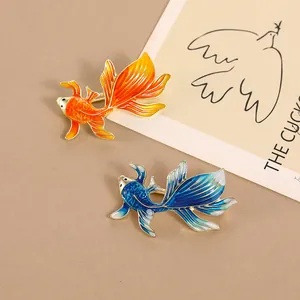 Chinese style enamel koi fish brooches in orange and blue with artistic gold outlines