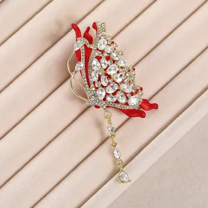 Détail macro d'une broche papillon en émail rouge avec cristaux et pendentif à pampilles