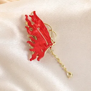 Broche papillon dorée élégante en émail rouge avec pampille en strass sur tissu satiné