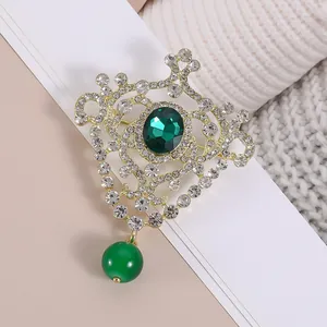 Elegant vintage crown brooch with emerald stones and rhinestones on gold hollow metal