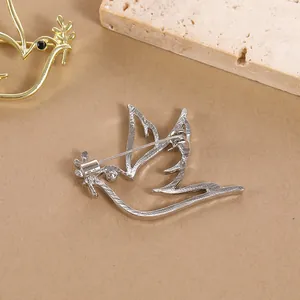 Back view of minimalist silver peace dove brooch with olive branch and pin closure