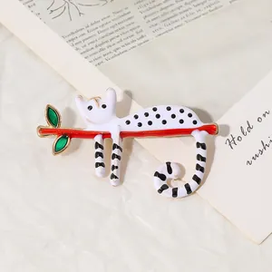 Broche créative en émail avec chat blanc sur une branche rouge et feuilles