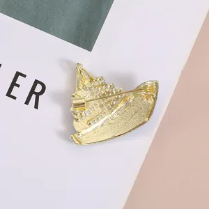 Broche de crucero dorado con esmalte azul y pedrería visto desde un ángulo lateral