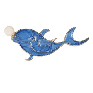Broche baleine en émail bleu avec perle blanche sur une base en métal doré minimaliste