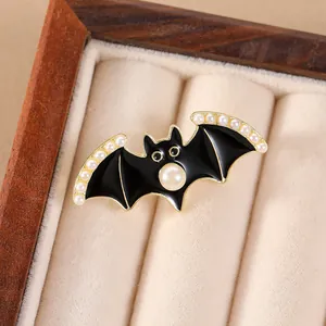 Détail d'une broche chauve-souris en émail noir avec perles blanches sur écrin