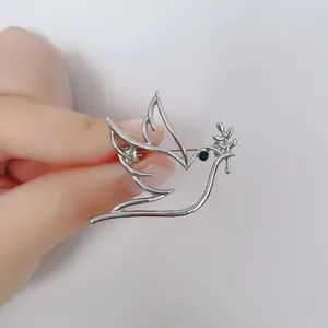 Minimalist silver hollow peace dove brooch with olive branch and blue gemstone eye