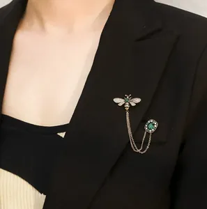 Elegant vintage bee brooch with emerald stones and gold tassels on a black suit blazer