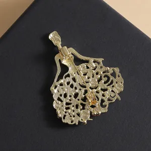 Back view of a gold-toned dancer brooch with intricate hollow patterns and safety pin
