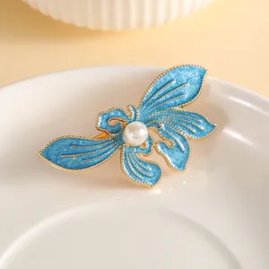 Elegant gold butterfly hair clip with blue enamel wings and a central pearl detail