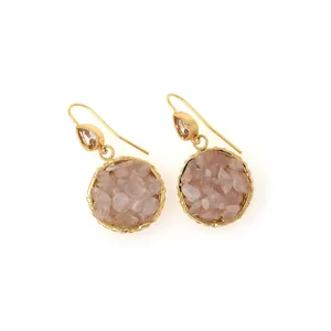 Detailed macro view of 18K gold-plated drop earrings featuring pink crushed gemstones
