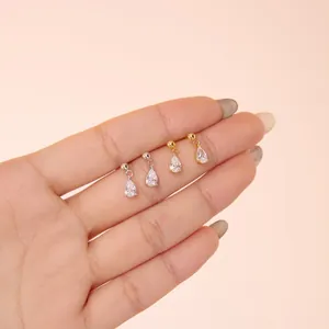 Hand holding silver and gold S925 sterling silver stud earrings with teardrop zircon