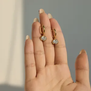 Macro view of gold-plated drop earrings with oval moissanite stones held by hand