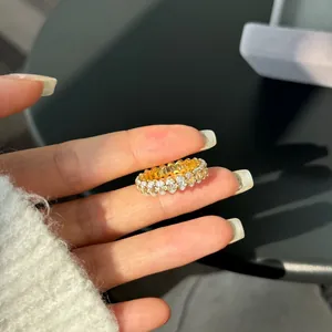 Close-up of a gold S925 silver ring with oval-cut white zircons worn on a finger