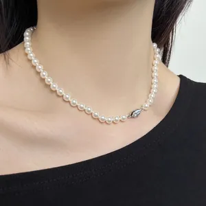 Detailed close-up of a white pearl necklace with silver clasp on a model neck